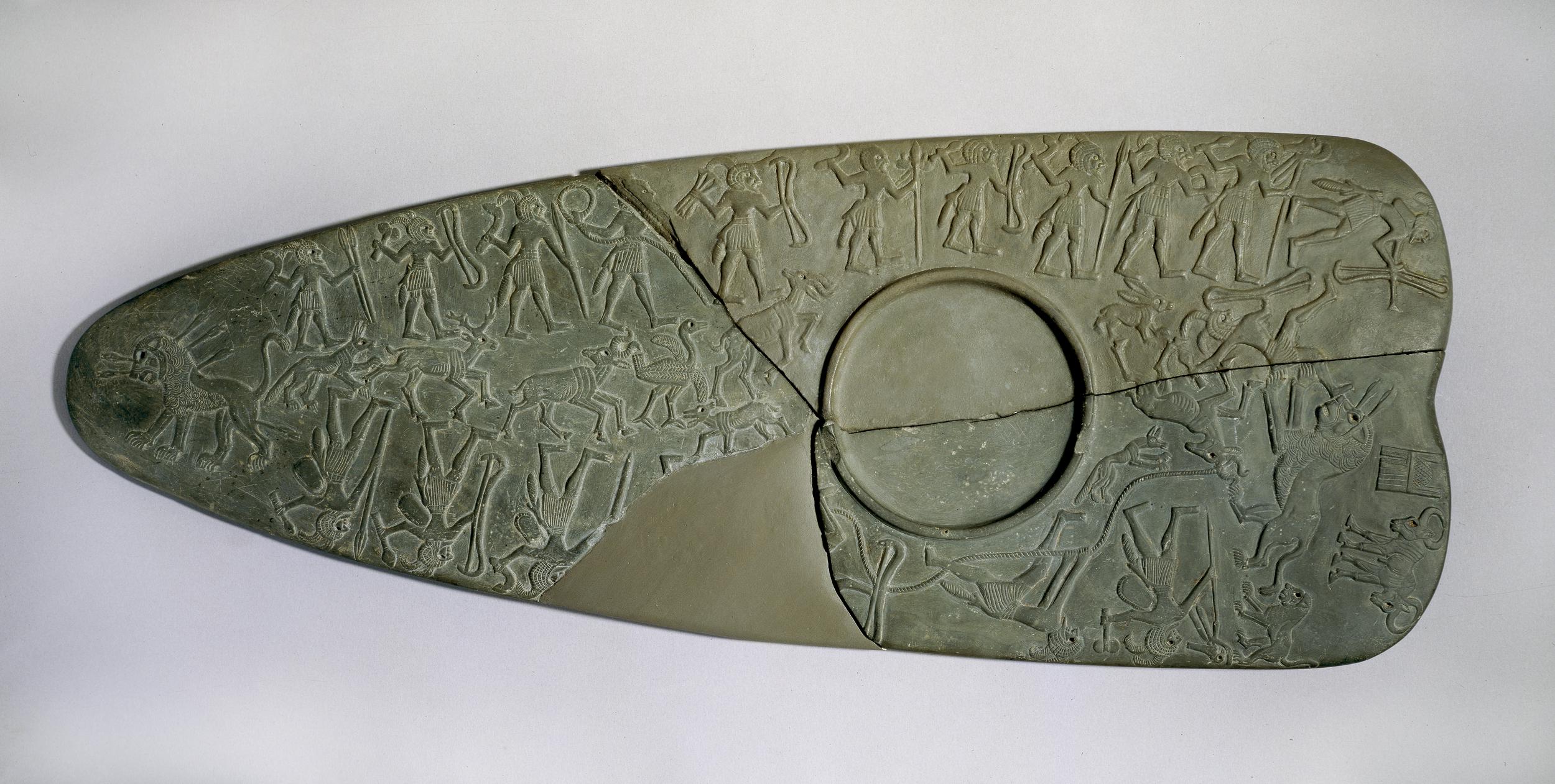 The Hunters’ Palette (BM EA 20790) depicting nineteen men and three hunting dogs in a lion hunt. Length: 30,5 cm. © The Trustees of the British Museum (CC BY-NC-SA 4.0).